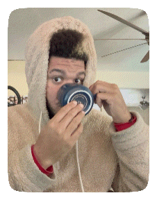 a man wearing a hoodie is drinking from a mug