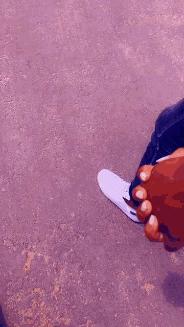 a person is holding another person 's hand while wearing a watch and a pair of shoes .
