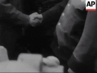 a black and white photo of two men shaking hands with an ap logo in the upper right corner