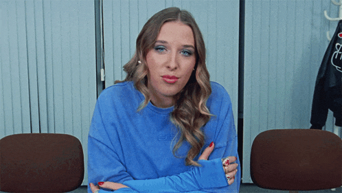 a woman wearing a blue sweatshirt that says esc is sitting in a chair with her arms crossed
