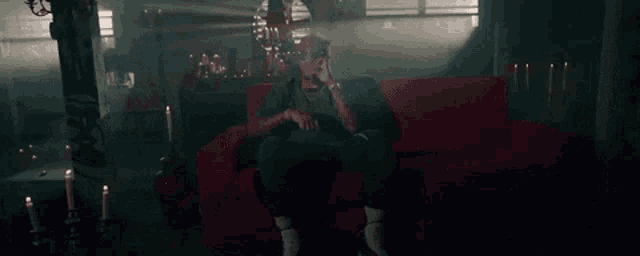 a man with dreadlocks is sitting on a couch lighting a cigarette with a lighter .