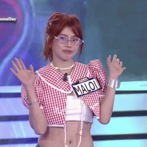 a woman wearing glasses and a crop top has a name tag that says maloi