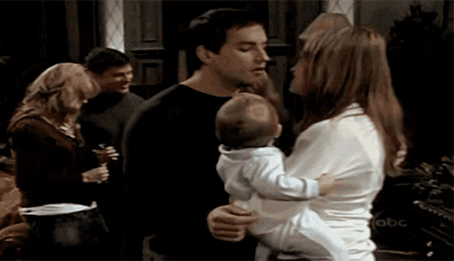 a man and a woman holding a baby with the abc logo in the corner