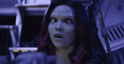 a woman with green hair is sitting in a chair with her mouth open and a surprised look on her face .