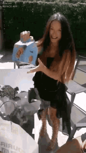 a woman in a black dress is holding a blue box in her hands .