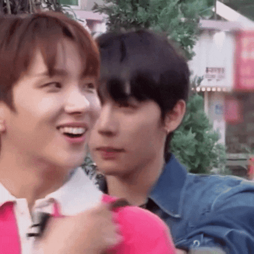 a close up of two young men standing next to each other and smiling .