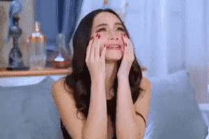 a woman is covering her face with her hands and smiling .