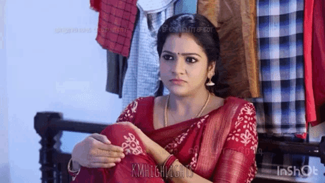 a woman in a red saree is sitting on a staircase with her hands on her knees .