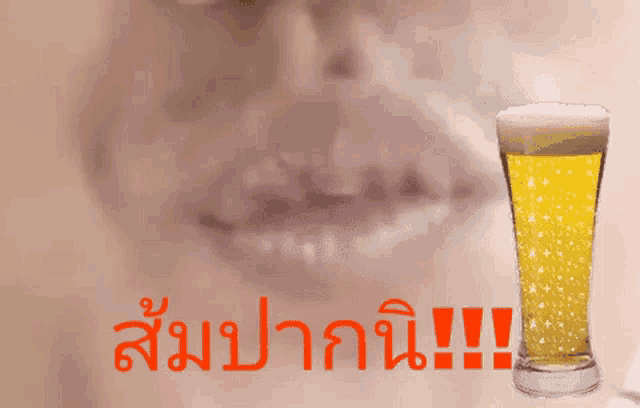 a glass of beer next to a person 's mouth with foreign writing