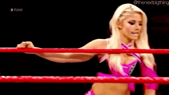 a woman is standing in a wrestling ring with a red rope .