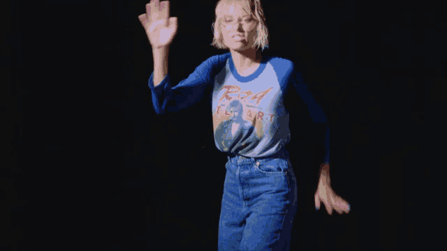 a woman wearing a rod stewart shirt waves her hand