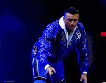 a man in a blue paisley jacket is giving a thumbs up