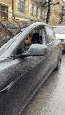 a woman is driving a tesla model 3 on a street