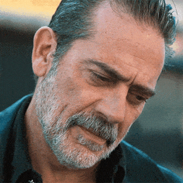 a man with a beard and a black shirt is looking down
