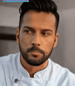 a man with a beard is wearing a white chef 's coat .