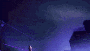 a person is standing in a dark room with purple light coming out of their head .