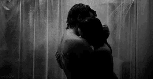 a man and a woman are hugging in the shower .