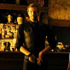 a man in a black shirt is standing in front of a shelf with a bottle that says ' x ' on it