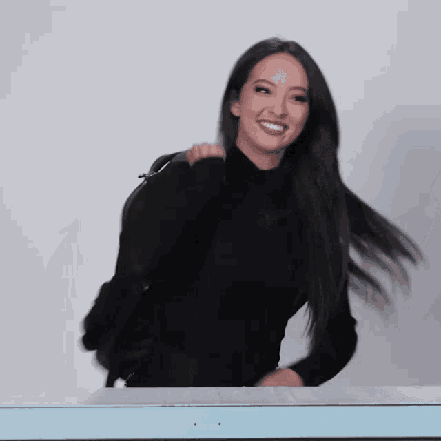 a woman wearing a black turtleneck and a black backpack