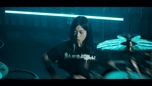 a woman playing a drum set in a dark room
