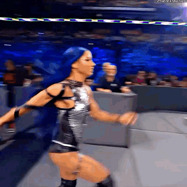 a female wrestler with blue hair is running on the ring