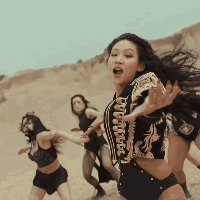 a group of women are dancing in the desert and one of them has a tattoo on her leg