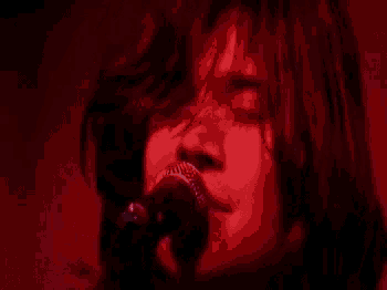 a close up of a person singing into a microphone with their eyes closed .
