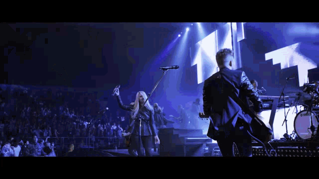 a man playing a guitar and a woman singing into a microphone on stage