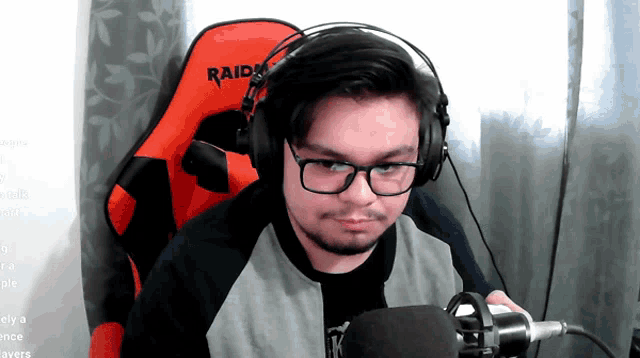 a man wearing headphones and glasses sitting in a raider chair