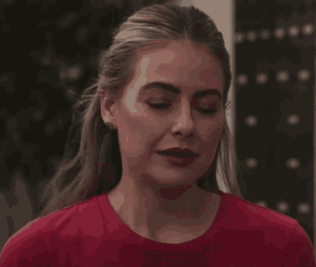 a woman wearing a red shirt and earrings is looking at the camera