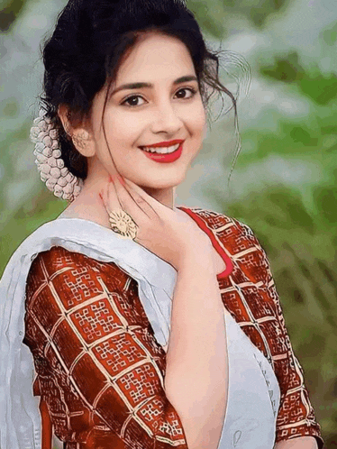 a woman wearing a white blouse and a brown and white blouse smiles for the camera