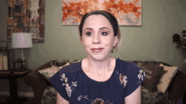 a woman in a blue shirt is sitting on a couch in front of a painting