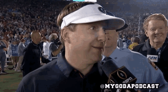 a man wearing a white visor is talking into a espn radio microphone