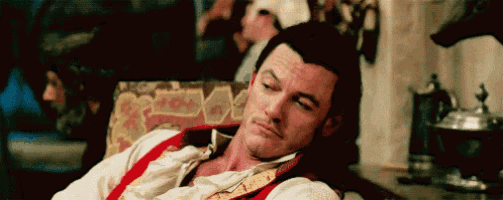 a man in a red vest and white shirt is sleeping on a couch .