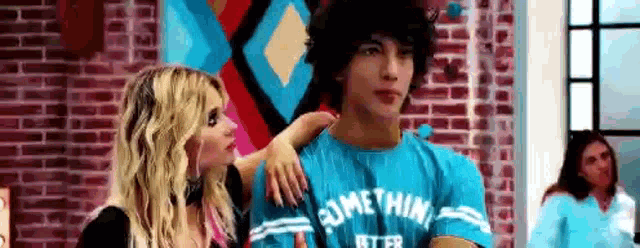 a woman is putting her arm around a man 's shoulder in a room .