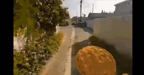 a person is riding a bike down a street with a sponge in the foreground