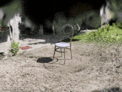 a chair is sitting in the dirt in front of a blurred background