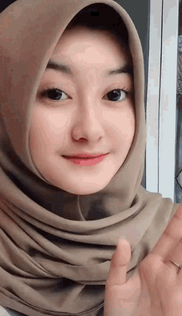 a woman wearing a hijab is smiling and giving the middle finger