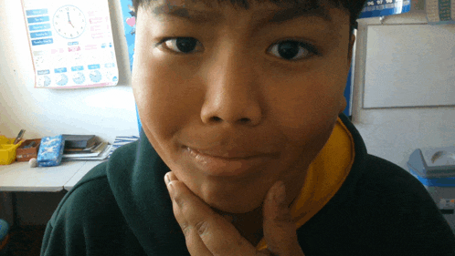 a young boy is making a funny face in front of a clock that shows the time as 10:10