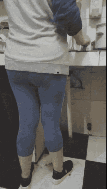 a woman wearing blue leggings and a grey shirt with the letter h on the back