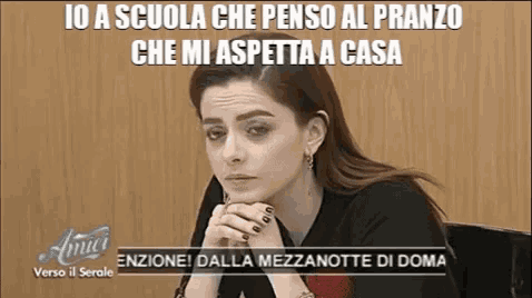 a woman is sitting with her head resting on her hands and a caption that says io a scuola che penso al pranzo