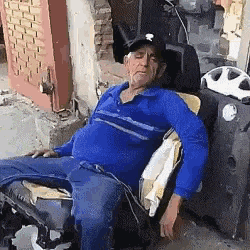 a man in a blue shirt is sleeping in a chair outside .