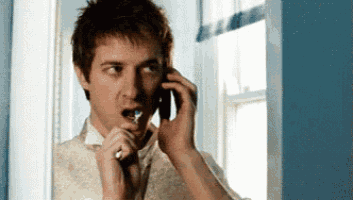 a man brushing his teeth while talking on a cell phone
