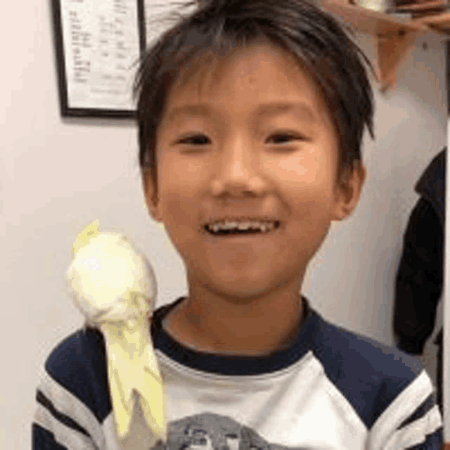 a young boy is holding a parrot in his hand and smiling at the camera .
