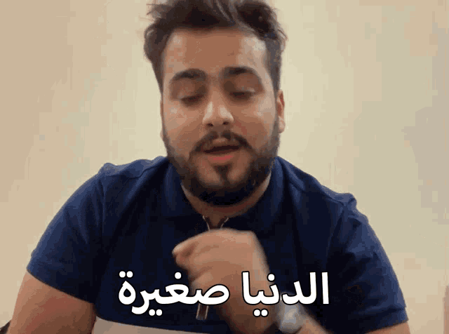 a man with a beard is wearing a blue shirt with arabic writing