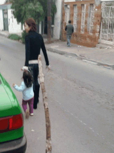 a woman walking down the street with a little girl