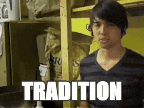 a man in a striped shirt is standing in a room with the word tradition written on the bottom .