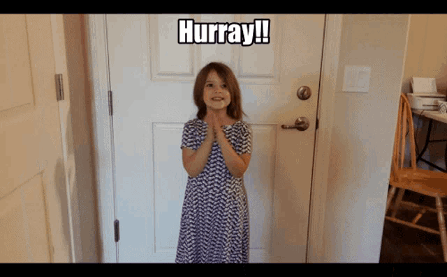a little girl standing in front of a door with hurray written on the top