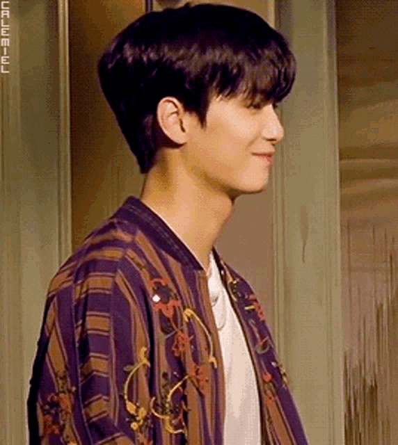 a young man wearing a purple and brown striped shirt and a white shirt