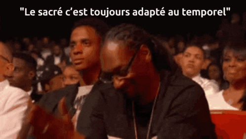 snoop dogg is sitting in a crowd with a caption that says " le sacré c'est toujours adapté au tempore "